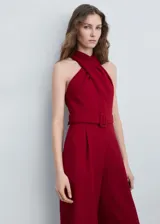 Mono largo de poliéster color rojo con cuello halter cruzado, sin mangas y cinturón con hebilla.