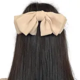 Moño grande color beige confeccionado en tela texturada con clip metálico en la parte trasera.