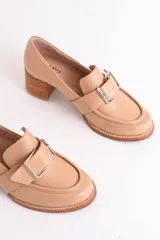 Mocasín de cuero color marrón con hebilla metálica plateada y taco de madera.