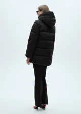 Campera puffer larga color beige, con capucha, cierre frontal con cremallera y bolsillos laterales con cierre.