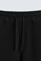 Bermuda negra de corte relaxed fit, con cintura elástica ajustable con cordón, bolsillos frontales y bolsillo trasero de parche.