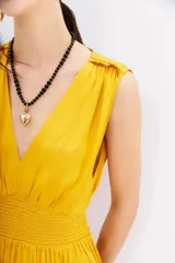 Vestido largo color amarillo mostaza, con escote en V, sin mangas y cintura elastizada con lazo.