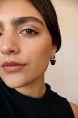 Aros de acero quirúrgico hipoalergénico con forma de argolla plateada y dije circular colgante de piedra natural color azul.