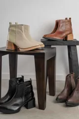 Bota corta de cuero marrón con puntera redondeada y taco cuadrado. Presenta una correa con hebilla alrededor del tobillo y cierre lateral.