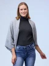 Cardigan negro de tejido suave, estilo poncho o capa, con cuello tipo chal y mangas amplias.
