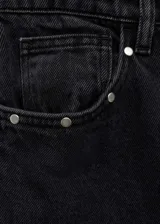 Pantalón de jean negro de corte recto con tachas plateadas en los laterales.