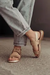 Sandalias bajas doradas de cuero, con dos tiras anchas en el empeine y hebilla lateral ajustable.