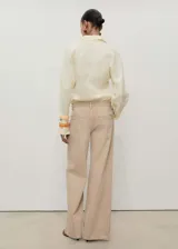 Pantalón de jean color beige, de corte wideleg, tiro bajo, con cinco bolsillos y cierre frontal con cremallera y botón.