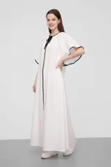 Túnica blanca de algodón con mangas cortas anchas y cuello en V con cordón negro. Presenta ribetes negros en cuello y mangas.