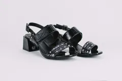 Sandalias de cuero con estampado animal print de vaca en blanco y negro, con detalles de tachas plateadas. Tienen correa trasera con hebilla y taco cuadrado de 5 cm.