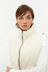Chaleco puffer color crema con cierre frontal y cuello alto.