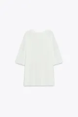 Remera blanca de punto liso, corte amplio, cuello redondo y manga corta.