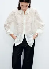 Camisa blanca con bordado de flores y detalles calados, de corte recto y manga larga con puños abotonados. Confeccionada en lyocell y poliéster.