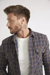 Sobrecamisa de viyela para hombre con estampado de cuadros en rojo y negro. Presenta cierre frontal con botones, bolsillos en el pecho con solapa y botón, y un interior capitoneado para mayor abrigo. Cuenta con un logo en grifa de cuero.