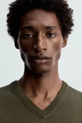 Jersey verde oscuro de punto fino, con cuello en V y mangas largas.