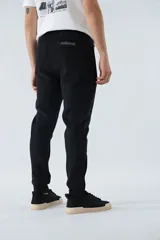 Pantalón de jogging negro de felpa con logo estampado y en goma, bolsillos con cierre, cierres en los tobillos, cintura ajustable y puños.