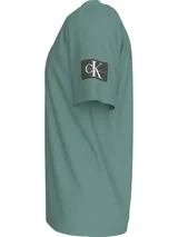Remera verde de corte clásico y manga corta, con cuello redondo y logo de Calvin Klein en la manga.