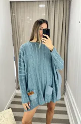 Sweater tejido de punto color fucsia con diseño de trenzas verticales en color naranja. Tiene cuello redondo y dos bolsillos frontales.