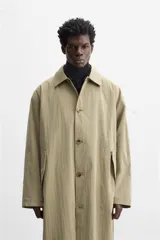 Gabardina color beige de corte amplio, con cuello solapa, manga larga, bolsillos laterales con solapa y cierre frontal con botones.