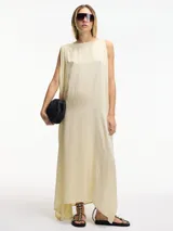 Vestido largo color crema, de corte amplio y cuello redondo. Presenta tajos laterales verticales.