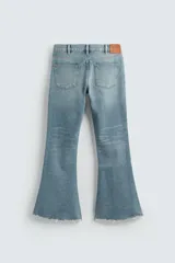 Pantalón de jean celeste, de tiro medio, corte ajustado en la parte superior y acampanado desde la rodilla. Tiene cinco bolsillos, efecto lavado y bajo irregular.