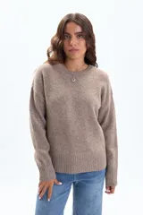 Suéter de tejido de punto color beige, con cuello redondo y manga larga. Presenta un calce relajado y puños y ruedo acanalados.