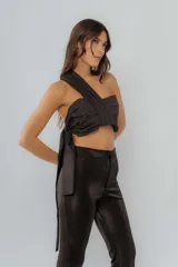 Top negro de un solo hombro con frunces y lazo lateral.