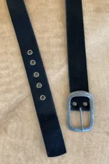 Cinto de cuero negro con textura de pelo, hebilla metálica plateada y ojales metálicos.