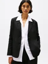 Blazer negro de lino con corte regular, solapas con muescas, botonadura sencilla, bolsillo de parche en el pecho y dos bolsillos delanteros de parche. Forro de algodón.