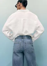 Jeans de mujer color azul claro, de tiro alto, corte wide leg y largo tobillero. Presenta bajo deshilachado, cierre de cremallera y botón, trabillas y bolsillos traseros.