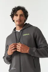 Campera de felpa color beige con capucha y cordón ajustable, cierre frontal, bolsillos con cierre, lettering estampado en la espalda y logo en grifa de goma.