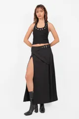 Top negro sin mangas con cuello halter, confeccionado en punto roma. Presenta escote embolsado con vista de algodón con lycra y elástico en su terminación para un mejor ajuste. Detalle de ojalillos color níquel en cuello y escote.