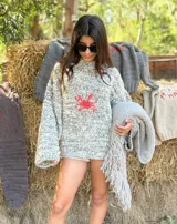 Sweater de punto jaspeado tejido a mano con lana Merino, de calce amplio y cuello alto. Cuenta con un bordado central de un cangrejo en color rojo y mangas largas holgadas.