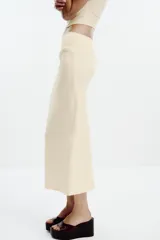 Falda midi color crema, de tiro alto con cintura elástica y detalle de pliegues laterales.