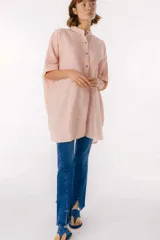 Camisa color salmón con rayas verticales blancas, cuello mao, manga corta con terminación en puño, botones de metal a la vista y tajos laterales.