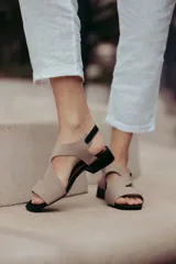 Sandalias de cuero color beige con tiras cruzadas y hebilla lateral. Taco cuadrado color marrón oscuro.