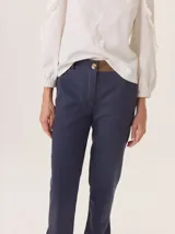 Pantalón de vestir color marrón, corte cigarette (pierna angosta) con tajo en el bajo. Presenta una cintura elástica ancha de color beige claro.