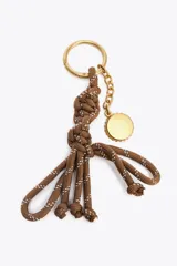 Charm para bolso con cuerda anudada color marrón y abalorios metálicos dorados.