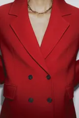 Abrigo rojo de lana con doble botonadura, cuello con solapa y bolsillos con solapa en la parte delantera.