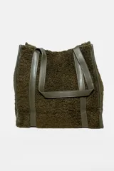 Bolso tipo tote bag color verde oliva, con textura de peluche y detalles en cuero sintético.