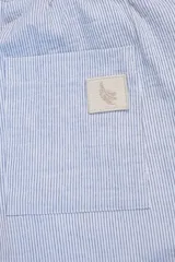 Pantalón celeste a rayas verticales blancas, confeccionado en tejido de algodón. Con cintura elastizada y cordón de algodón para regular el calce.
