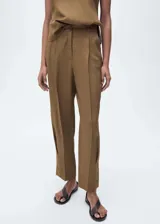 Pantalón de tiro medio color marrón, con trabillas, cierre delantero con cremallera y botón, dos bolsillos laterales, pinzas delanteras y diseño recto con aberturas en el bajo.