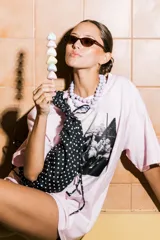 Bolso tipo cartera de nylon con diseño plisado y estampado abstracto en tonos claros.