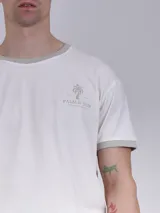 Remera blanca de corte recto, con cuello redondo y mangas cortas con ribete gris. Estampado pequeño con logo de la marca en el pecho.