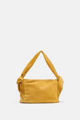 Bolso de mano color mostaza, de serraje, con asa ancha con detalles y cierre mediante hebilla metálica.