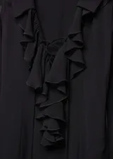 Vestido largo de tejido semitransparente negro con escote en pico, manga larga acampanada y detalle de volantes en el cuello.