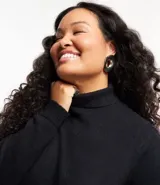 Vestido corto negro de punto ligero, con cuello alto y mangas largas.