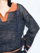 Buzo negro con cuello polo y calado, tejido a máquina con hilado serido y lurex, de estilo oversized.