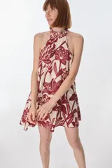 Vestido corto con estampado floral en tonos rojo y beige, cuello halter y corte evasé.