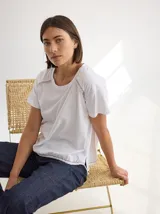 Remera blanca de algodón con cuello redondo y mangas cortas. Presenta detalle de costuras en hombros y ruedo. Corte recto y holgado.